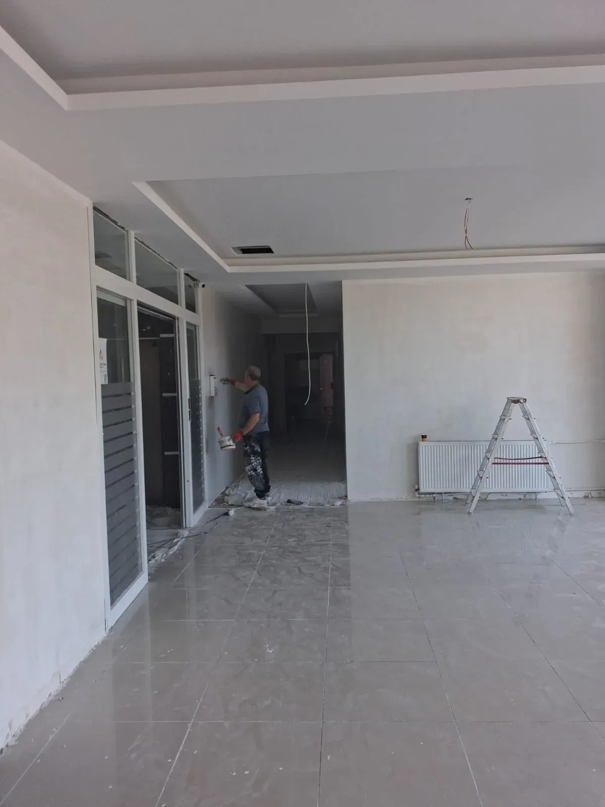 Usta mala ile duvara saten alçı çekerken, iş yeri boyama hazırlığı